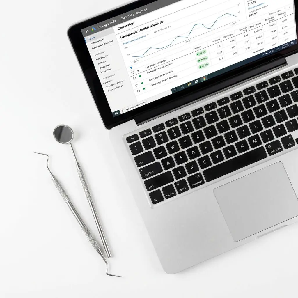 Laptop with dental Google Ads reporting beside dental tools